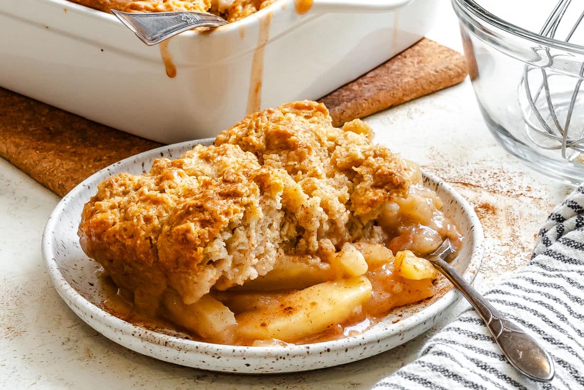 Une assiette de cobbler aux pommes à côté du plat de cuisson.