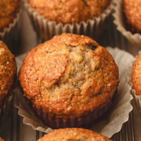A banana maple muffin with the parchment liner pulled out on it.