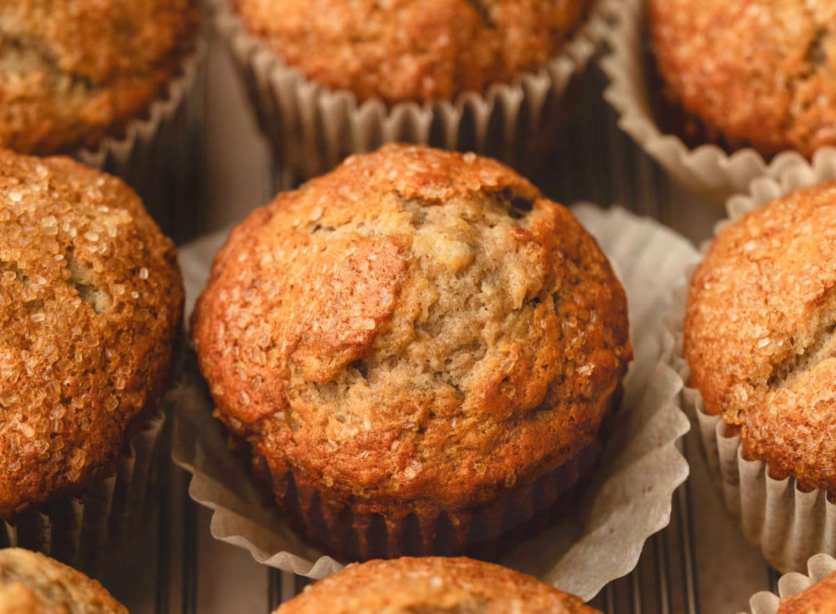 A banana maple muffin with the parchment liner pulled out on it.
