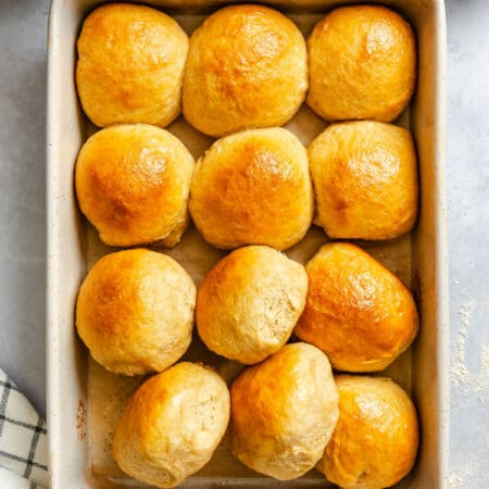 A pan of honey wheat rolls with some of the rolls turned sideways.
