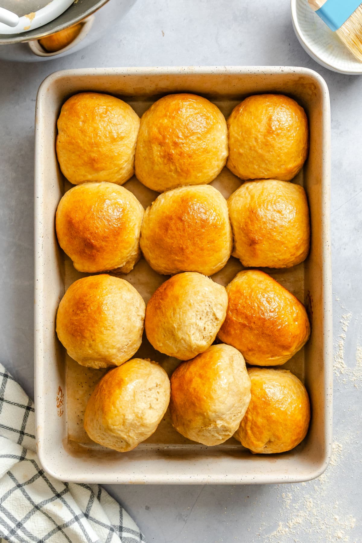 A pan of honey wheat rolls with some of the rolls turned sideways. 