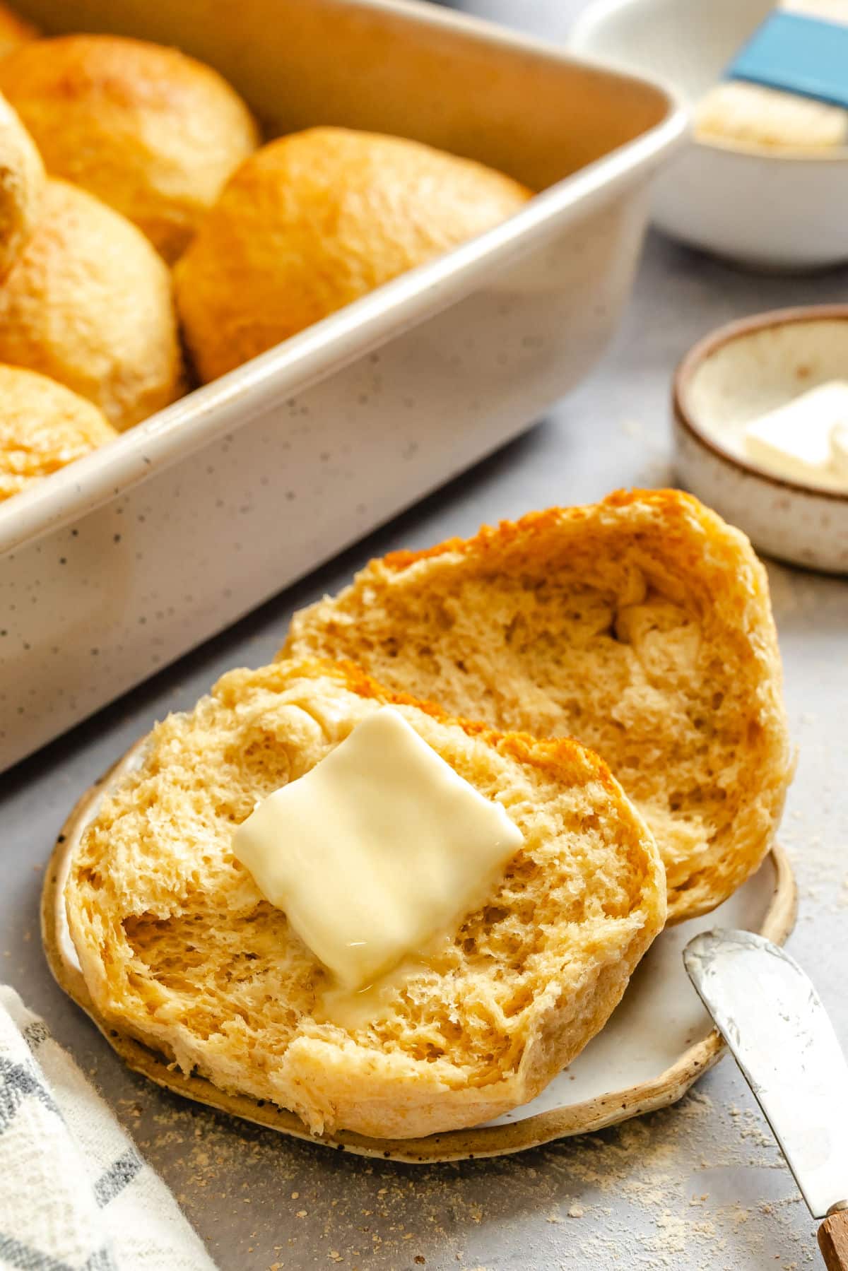 A honey wheat roll with a pat of butter melting on it. 