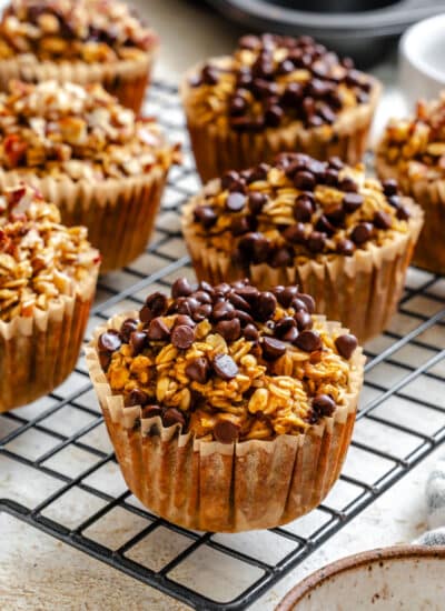 Pumpkin oatmeal cups topped with mini chocolate chips on a wire rack.