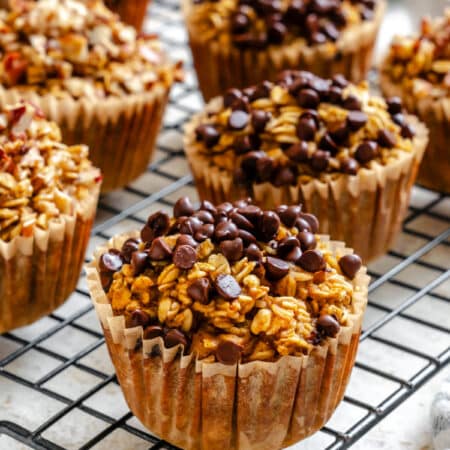 Pumpkin oatmeal cups topped with mini chocolate chips on a wire rack.