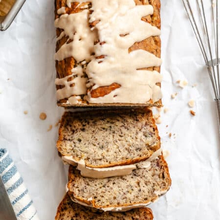A loaf of brown butter glazed banana bread with three slices cut from the loaf.