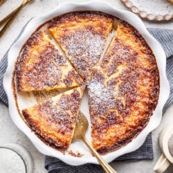 A buttermilk pie in the pan with a server cutting a piece.