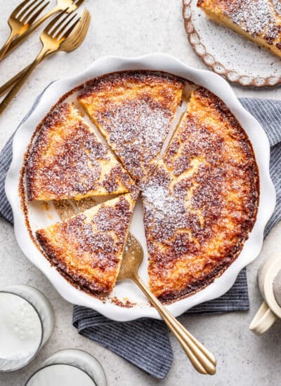 A buttermilk pie in the pan with a server cutting a piece.