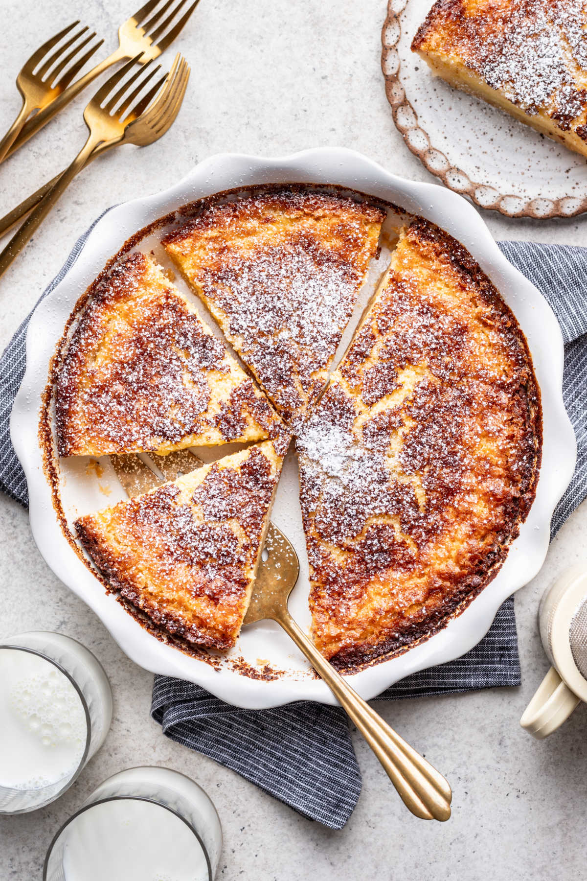 A buttermilk pie in the pan with a server cutting a piece.