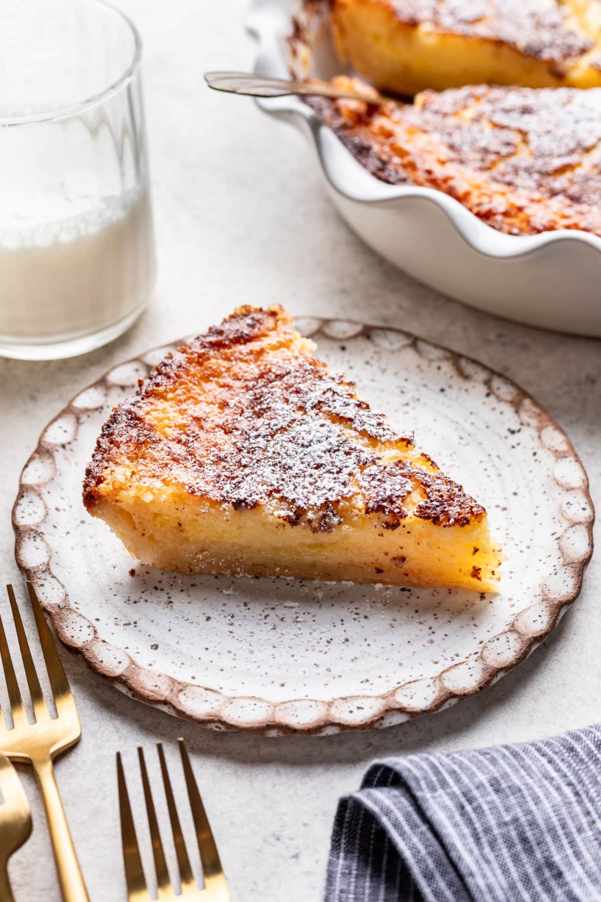 A slice of buttermilk pie on a plate next to the pie pan.