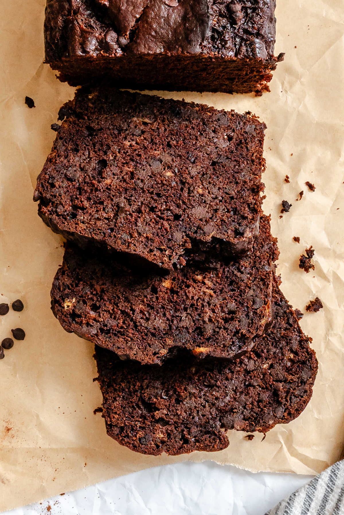 Chocolate Banana Bread Three slices of chocolate banana bread next to the loaf.