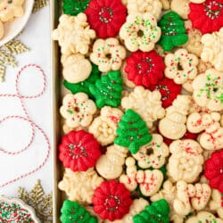A tray of spritz cookies next to sprinkles and ribbon.