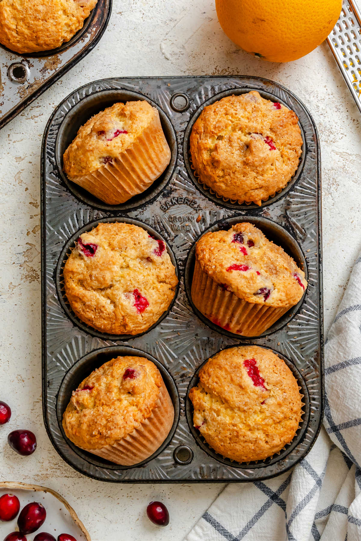 Six cranberry orange muffins at different angles in a muffin tin.