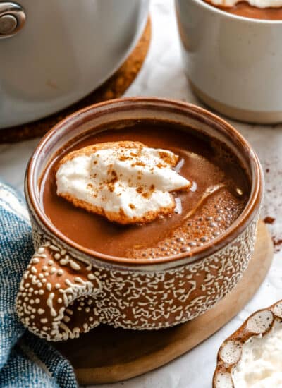 A cup of gingerbread hot chocolate topped with whipped cream.