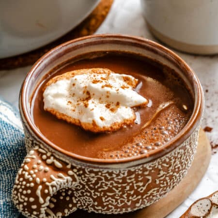 A cup of gingerbread hot chocolate topped with whipped cream.