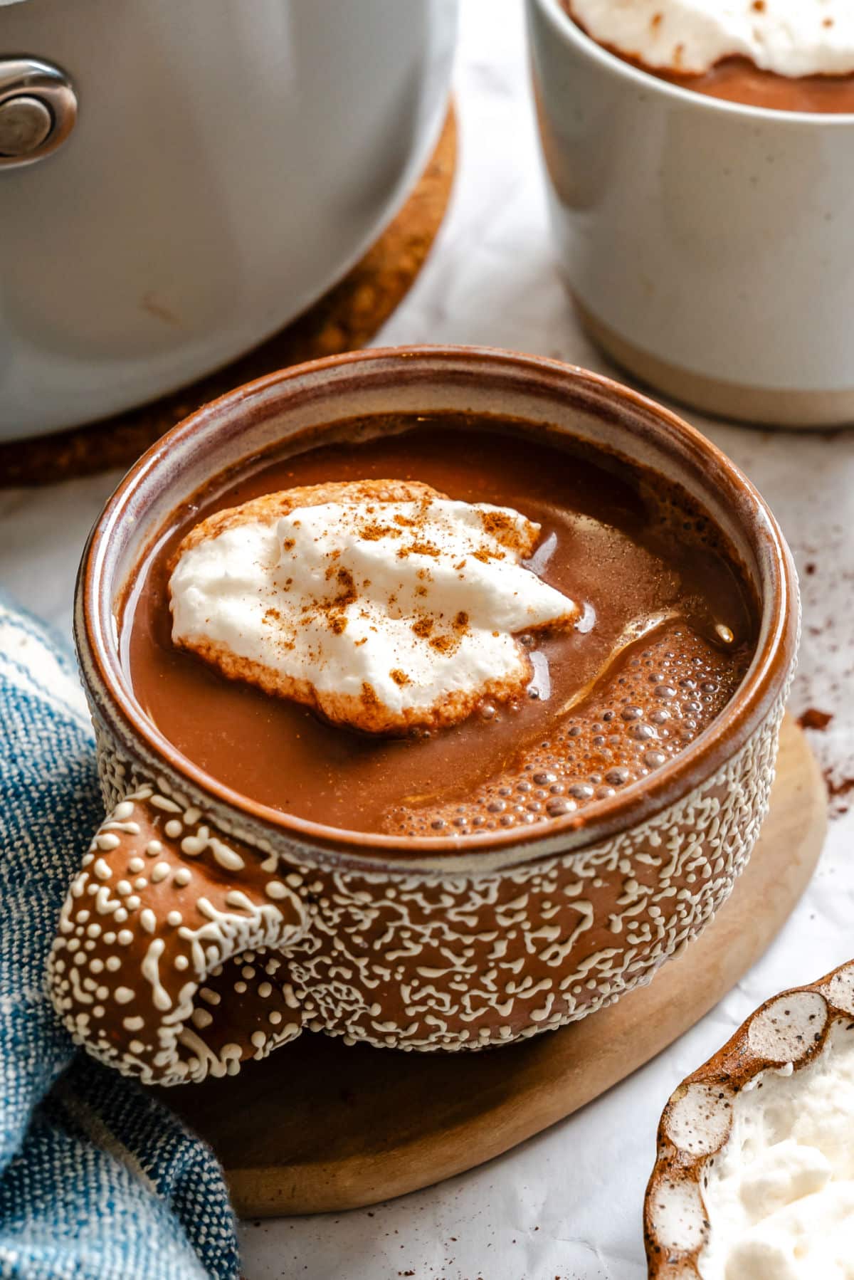 A cup of gingerbread hot chocolate topped with whipped cream.