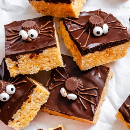 Stacked Halloween Rice Krispies treats on white parchment paper.