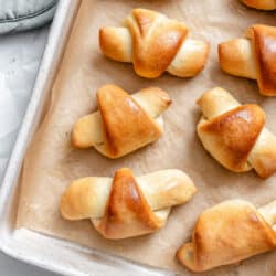 Baked homemade crescent rolls on a parchment lined tray.