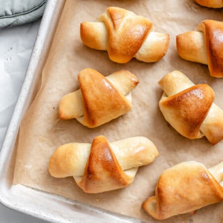 Baked homemade crescent rolls on a parchment lined tray.