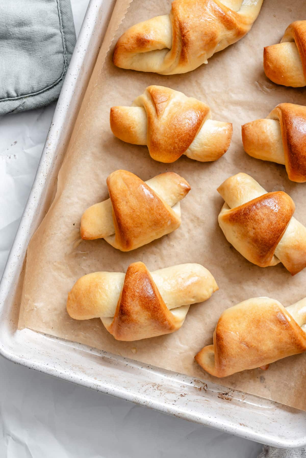 Baked homemade crescent rolls on a parchment lined tray.