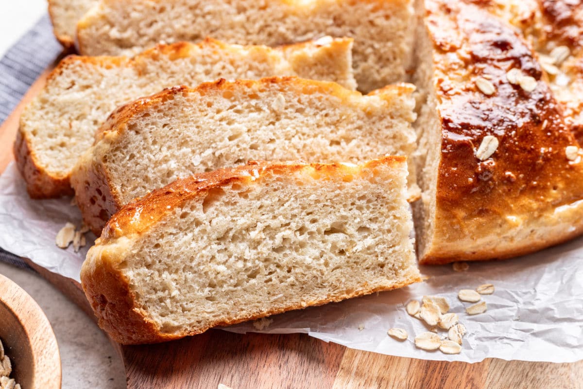 Slices of maple oat skillet bread on a wooden cutting board.