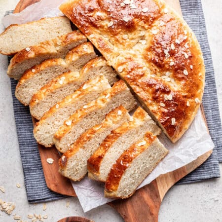 Half of a loaf of maple oat skillet bread sliced next to the rest of the loaf.