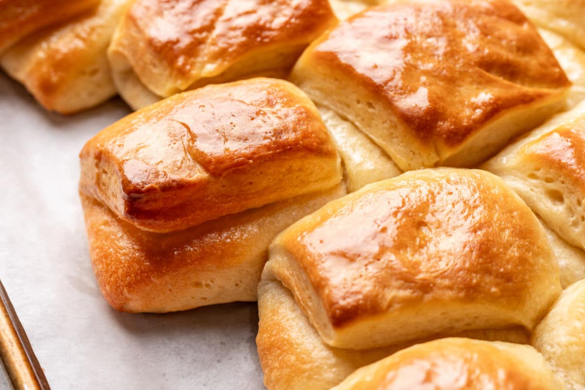 Parker House rolls in a row on a parchment lined tray.