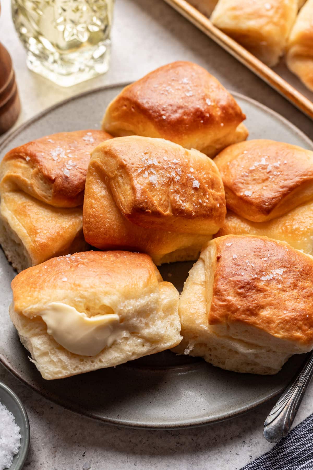 A plate of parker house rolls next to the tray and a dish of coarse salt.