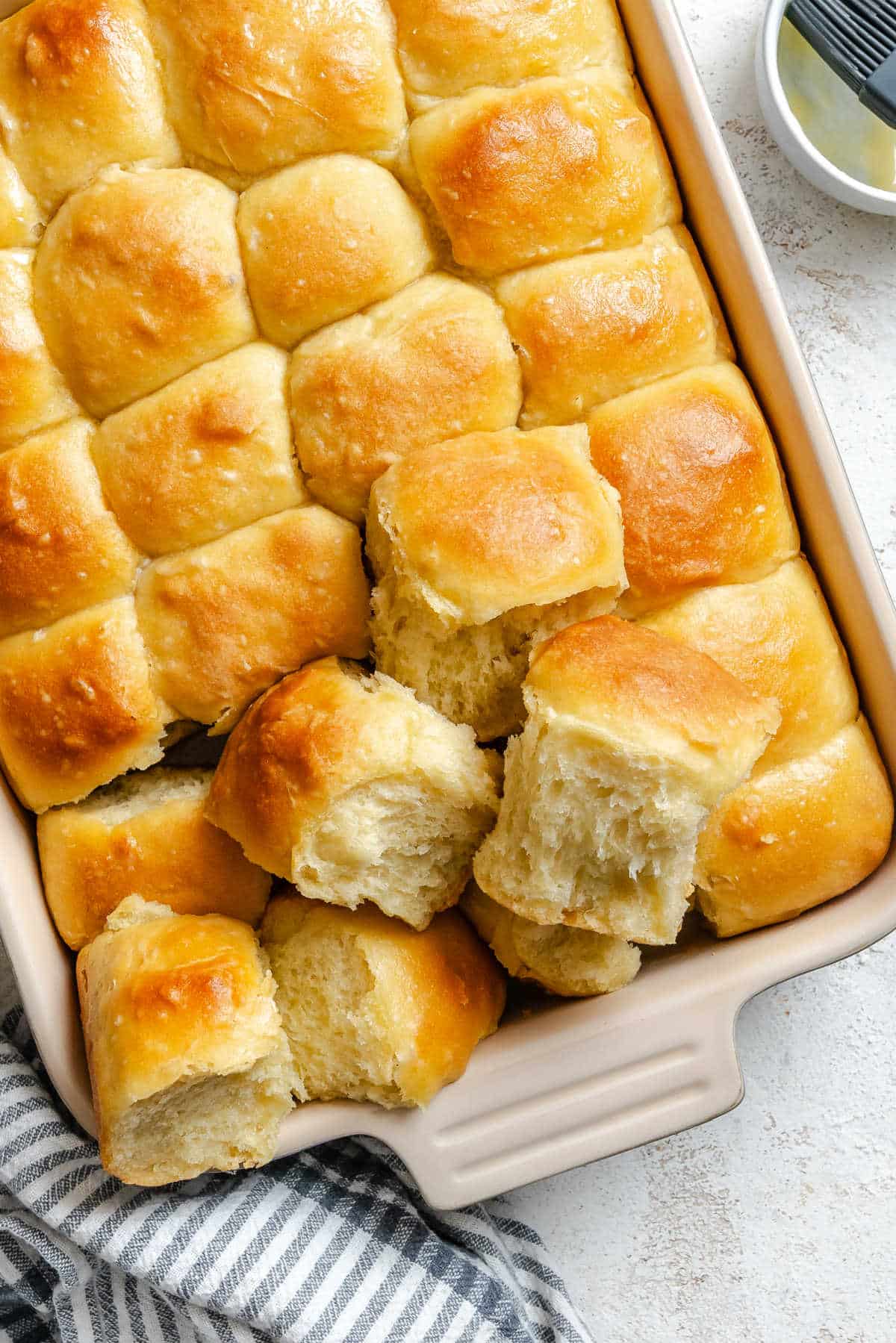 A pan of potato rolls next to a striped kitchen cloth.