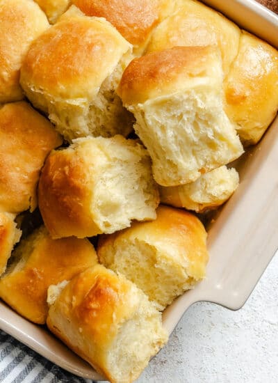 A few potato rolls overlapping in a pan of rolls.
