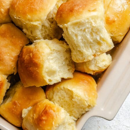 A few potato rolls overlapping in a pan of rolls.