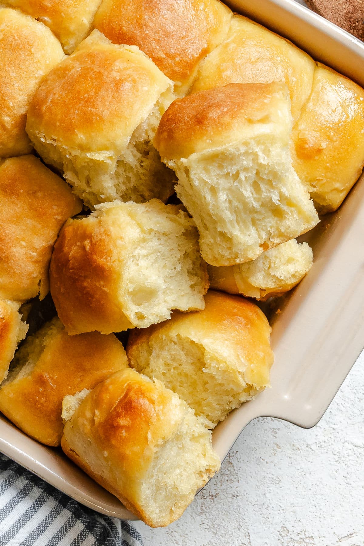 A few potato rolls overlapping in a pan of rolls.