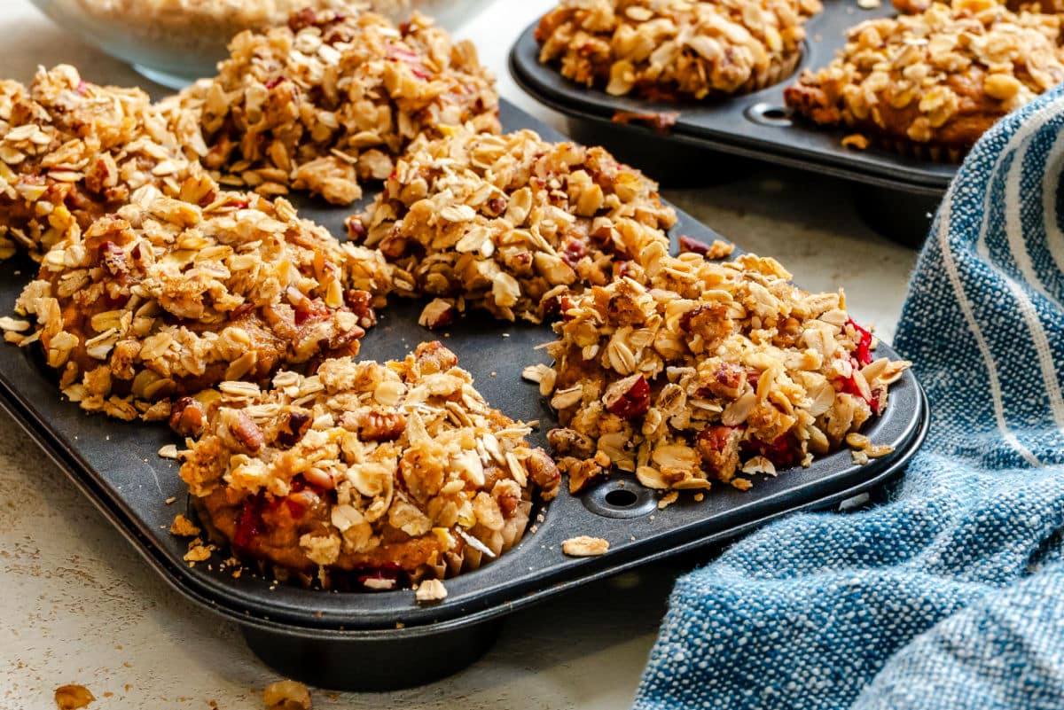 Baked pumpkin cranberry apple muffins in a muffin tin.