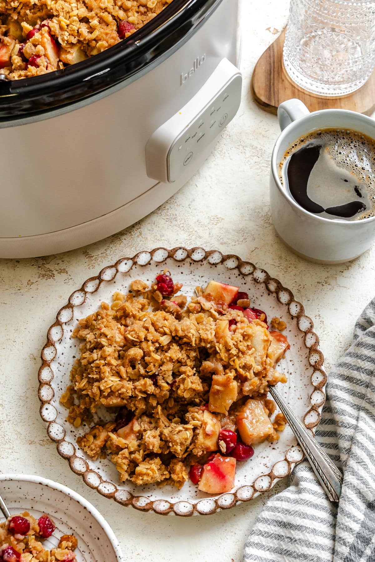 A plate of cranberry apple crisp next to the slow cooker. 