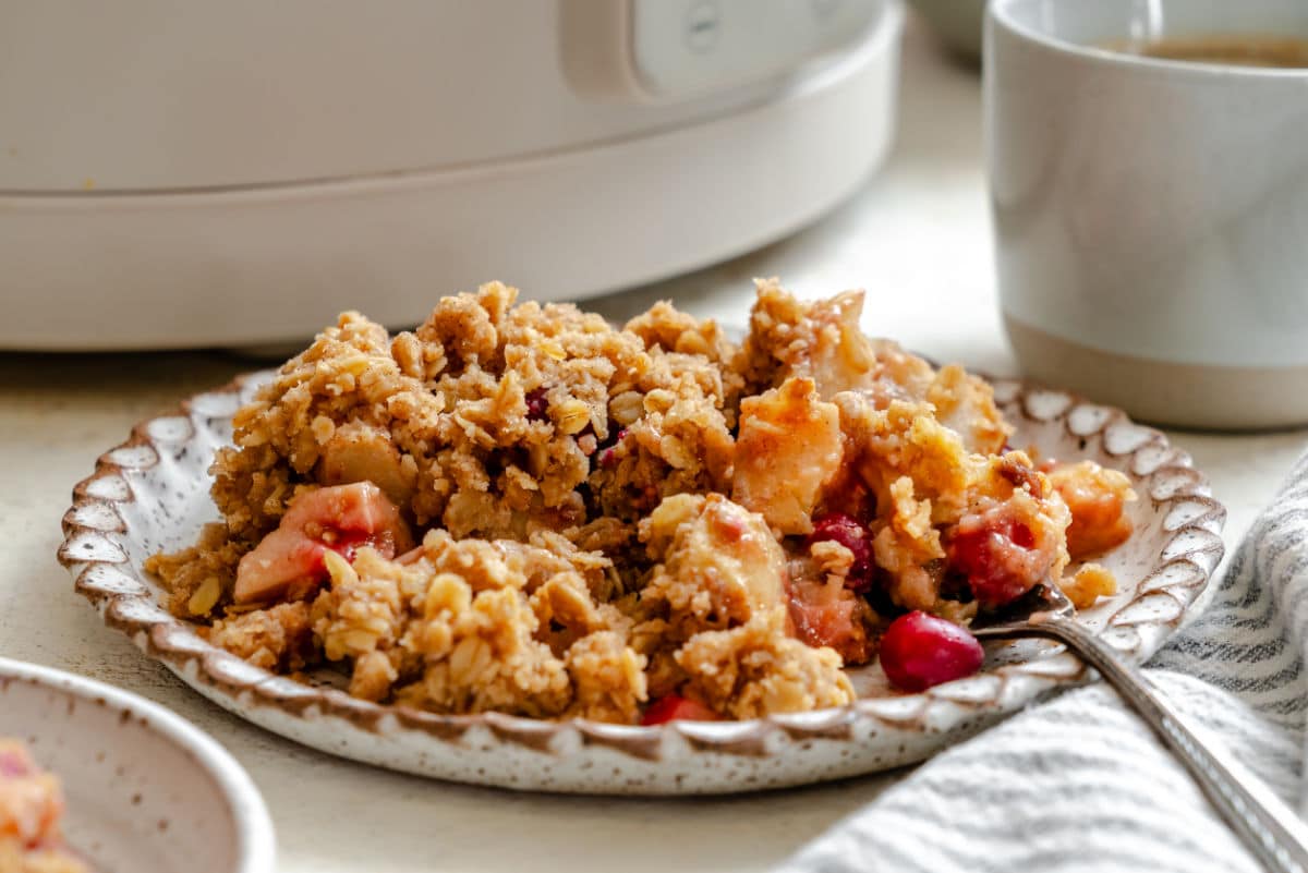 A plate of slow cooker cranberry apple crisp with a fork in it. 