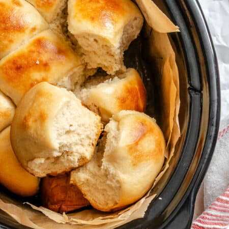 Slow cooker dinner rolls overlapping in a a crock pot.