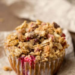 Pumpkin cranberry apple muffin on a piece of brown parchment paper.