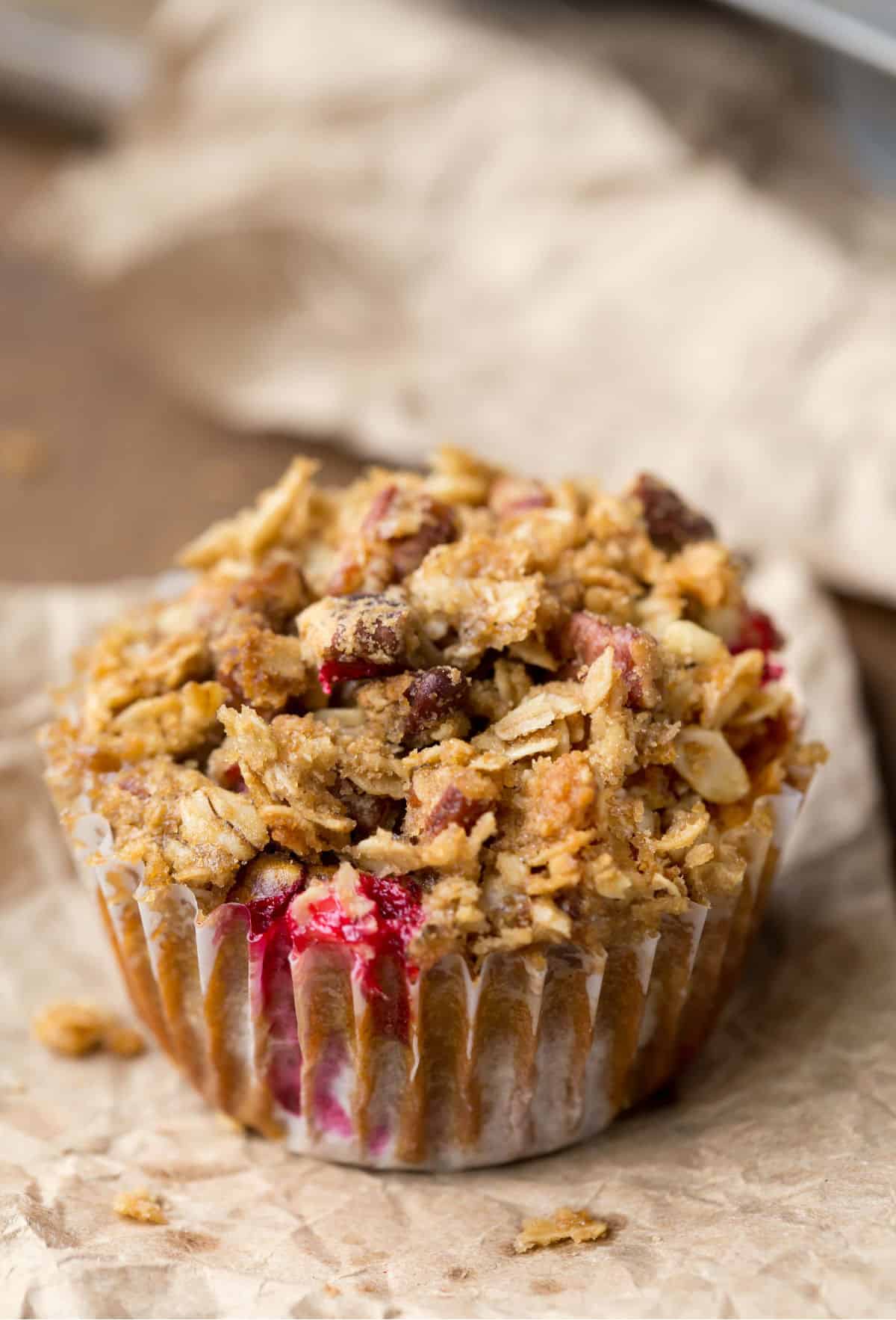 Pumpkin cranberry apple muffin on a piece of brown parchment paper. 
