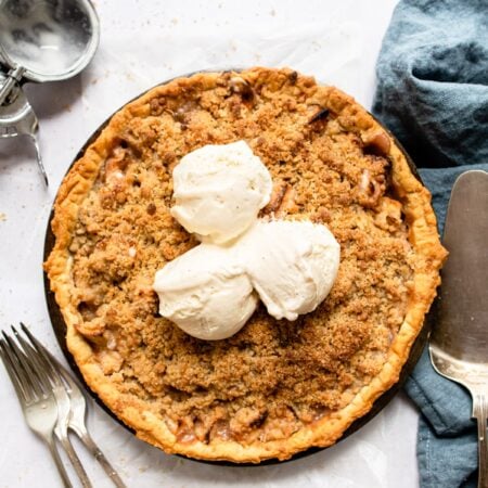Three scoops of vanilla ice cream on an apple pie.