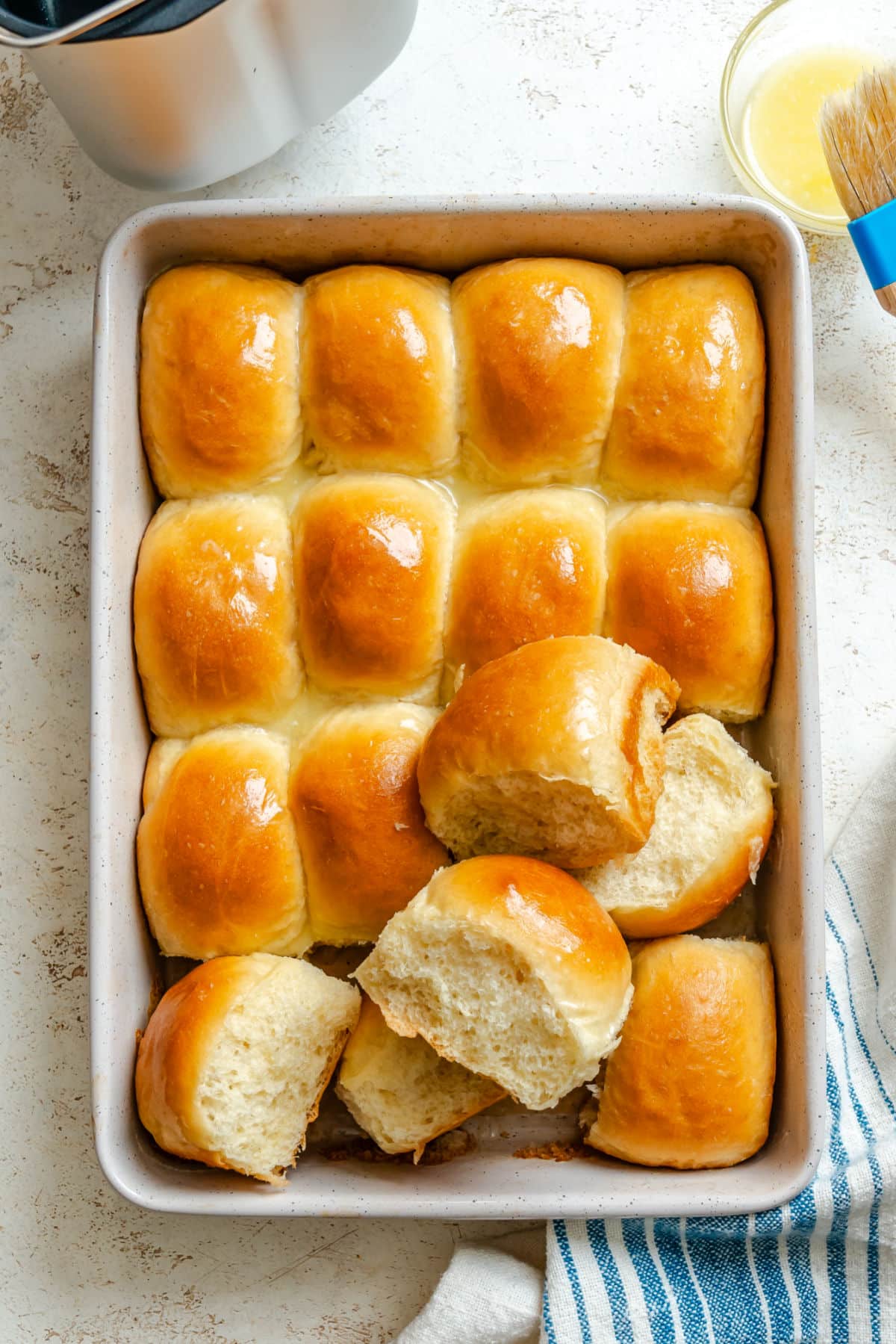 A pan of bread machine dinner rolls with a few on their side. 