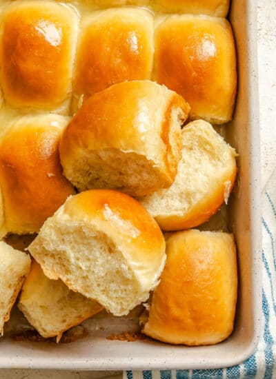 Two bread machine dinner rolls on top of the pan of dinner rolls.