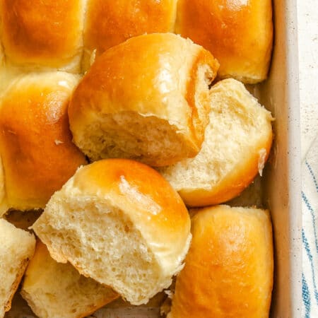 Two bread machine dinner rolls on top of the pan of dinner rolls.