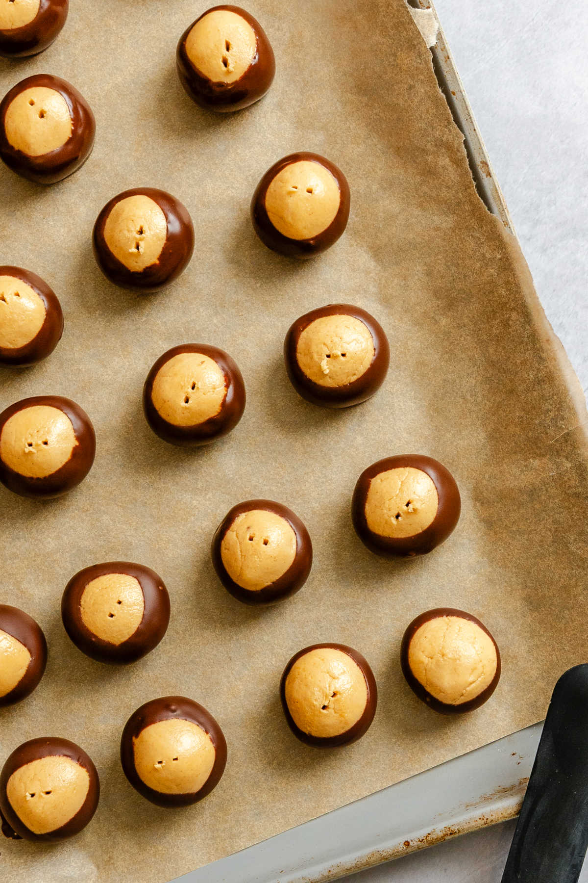 Buckeyes candy on a brown parchment lined pan.
