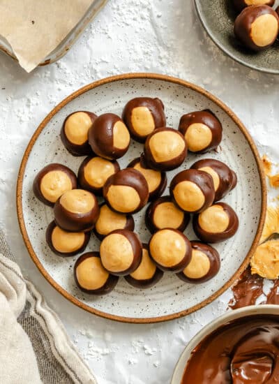 A plate of buckeyes candy next to a dish of melted chocolate.