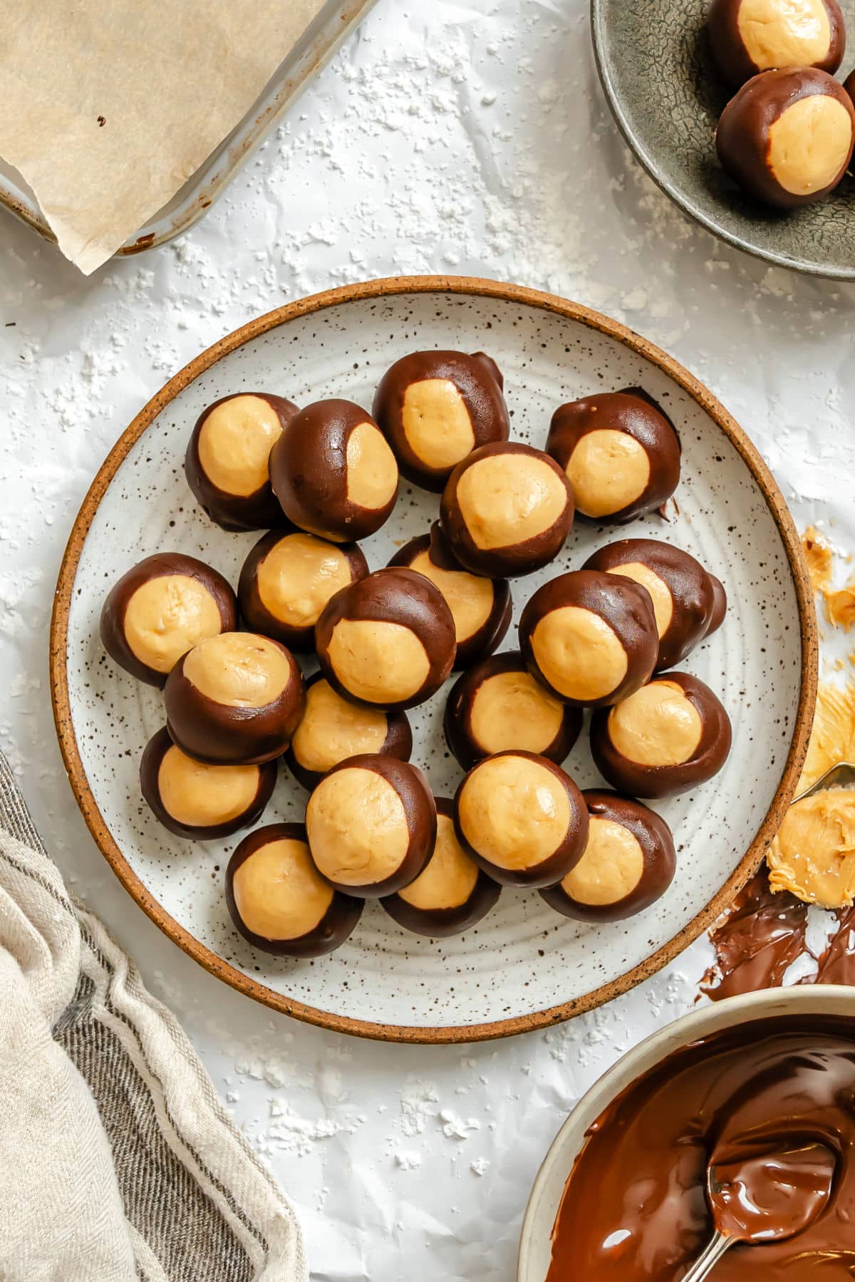 A plate of buckeyes candy next to a dish of melted chocolate.
