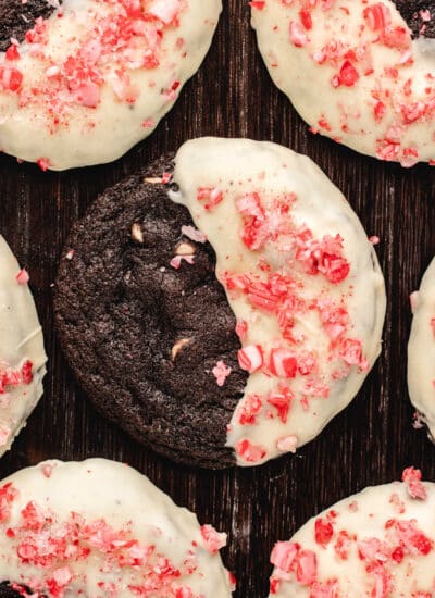 Half dipped chocolate candy cane cookies on a wooden background.