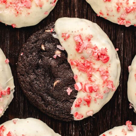 Half dipped chocolate candy cane cookies on a wooden background.