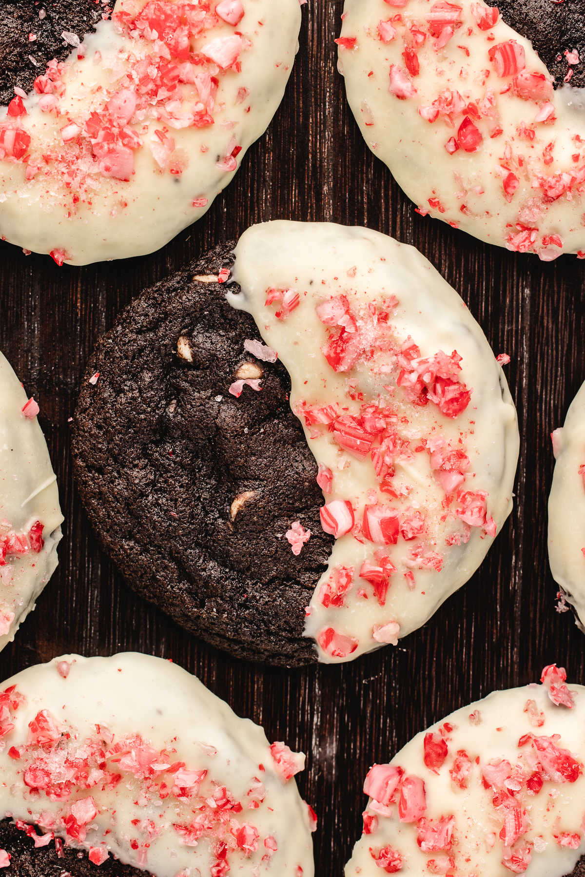 Half dipped chocolate candy cane cookies on a wooden background.