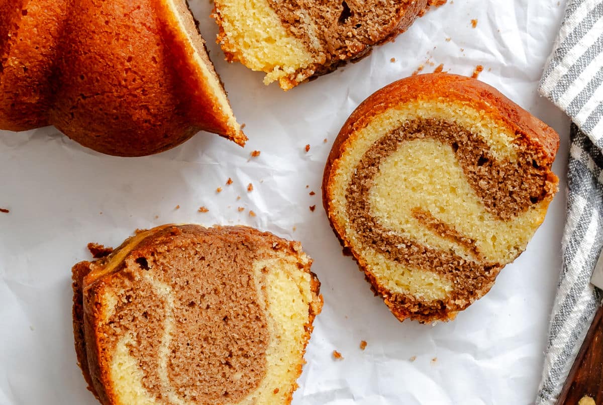 Slices of cinnamon swirl bundt cake on white parchment paper.