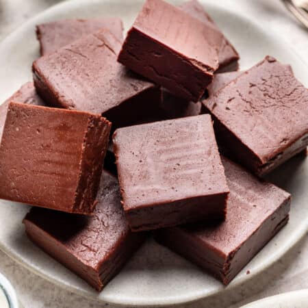A plate of chocolate fudge with pieces overlapping.