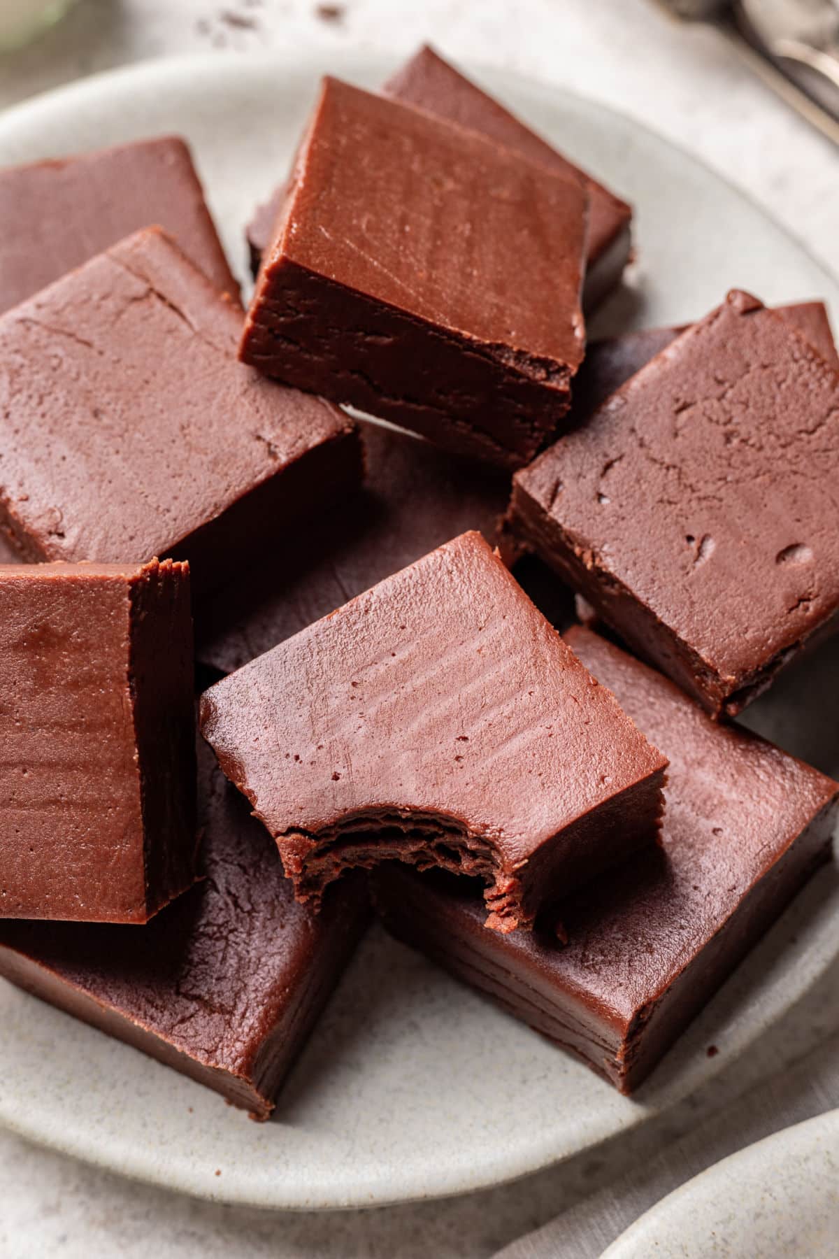 A piece of fudge with a bite out of it on top of other pieces of chocolate fudge. 